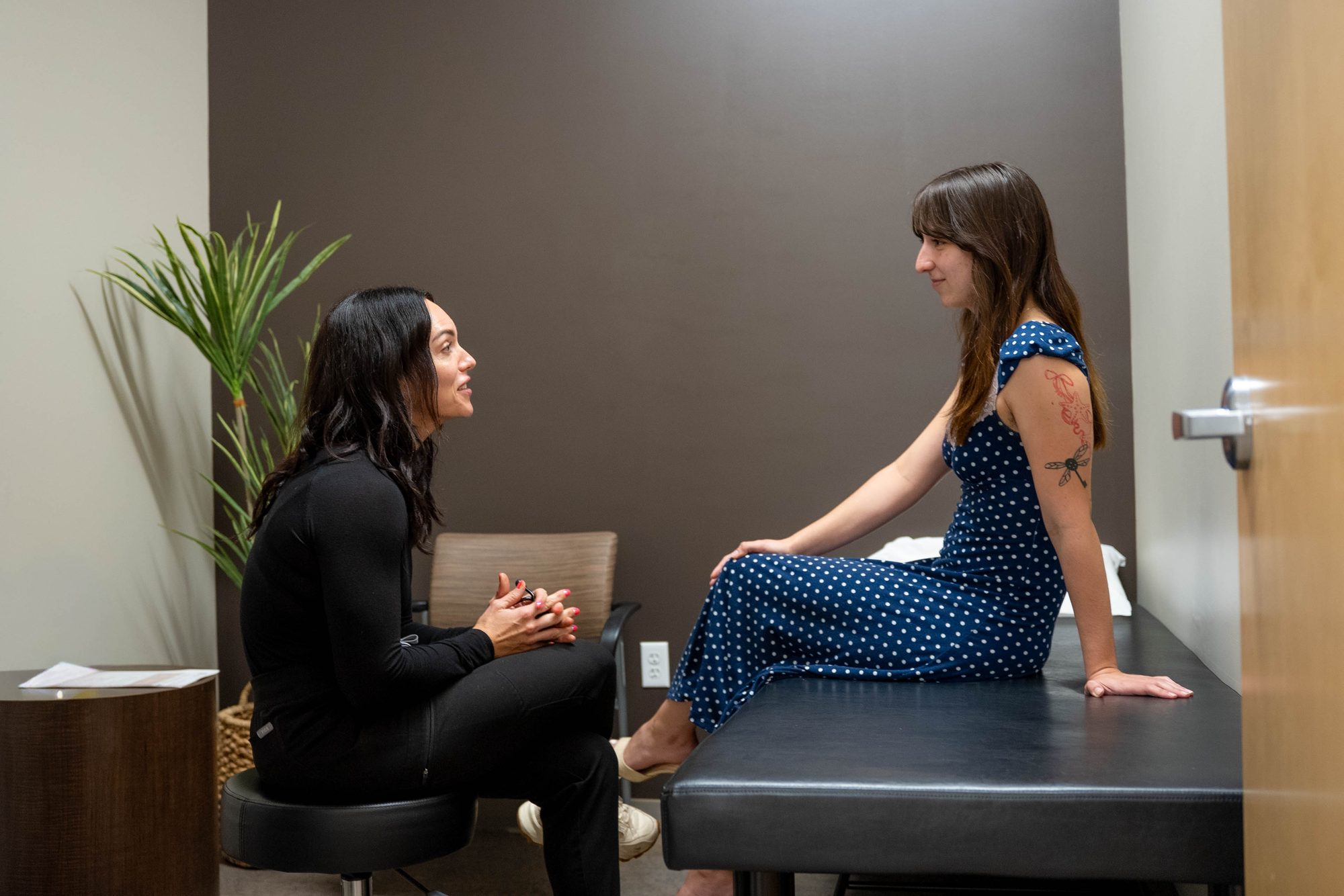 Deedee Keeler sitting and talking with a patient in an exam room at Prime Direct Health in Gilbert
