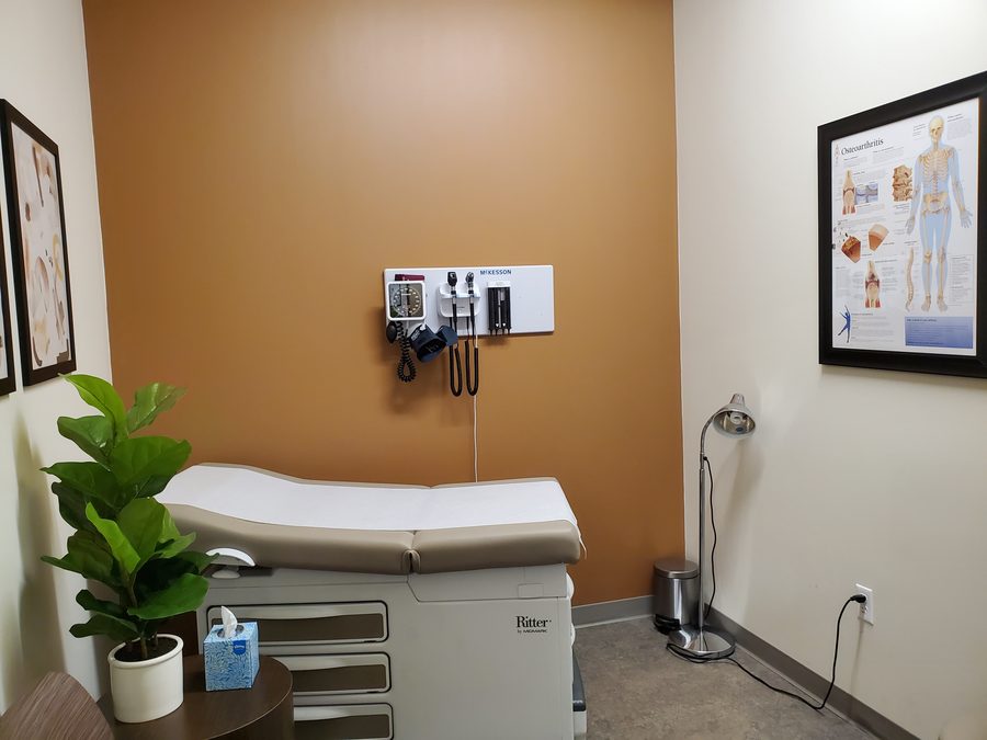 A Prime Direct Health exam room with exam table and wall-mounted scopes