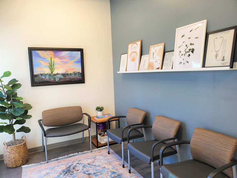 The Prime Direct Health waiting room with seating and a shelf of framed art